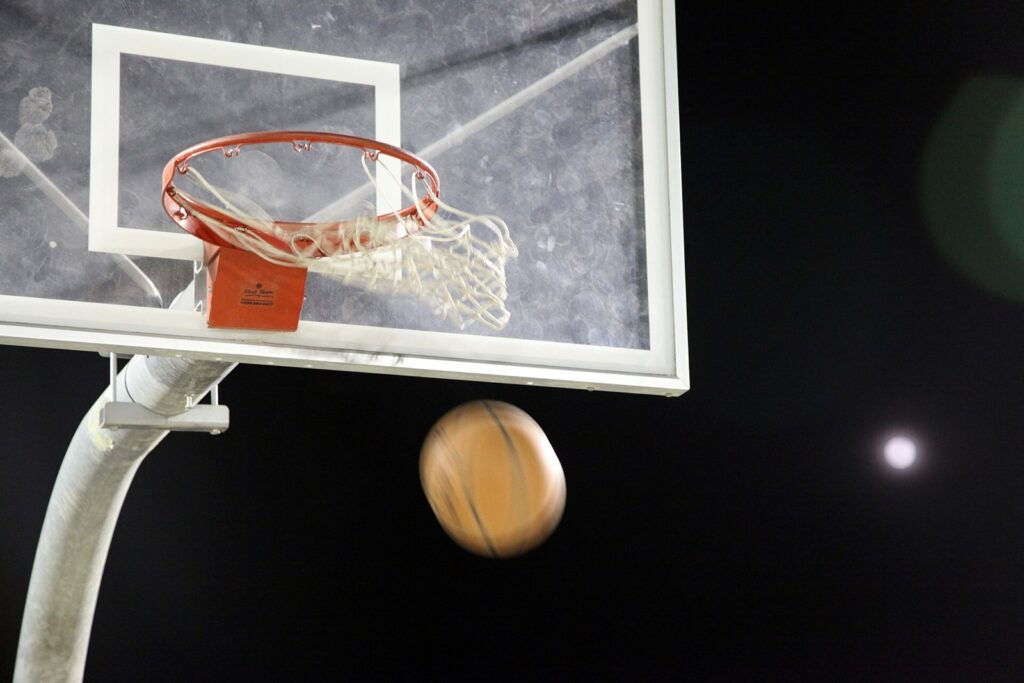 Basketball dropping toward a hoop under lights at night
